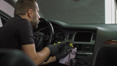 Klimanın havalandırma borularını buharla temizliyor ve arabanın kuaförünü üflüyor. Adam araba yıkamada çalışıyor, arabayı dezenfekte ediyor, temizliyor.