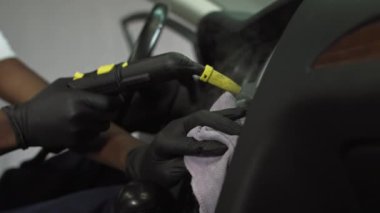 Afro-Amerikan öğrenci iş başında, bakteri ve virüslerden buharlı araba paneli, tozdan ve mikroplardan içini temizliyor, arabanın içinde ateş ediyor.