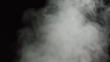 Beyaz buhar döner ve tavadan yükselir. Çerçevenin arkasındaki büyük bir çömlekten beyaz duman yükselir. İzole edilmiş dikişsiz döngü siyah arkaplan... Duman Akımı Efekti 4K