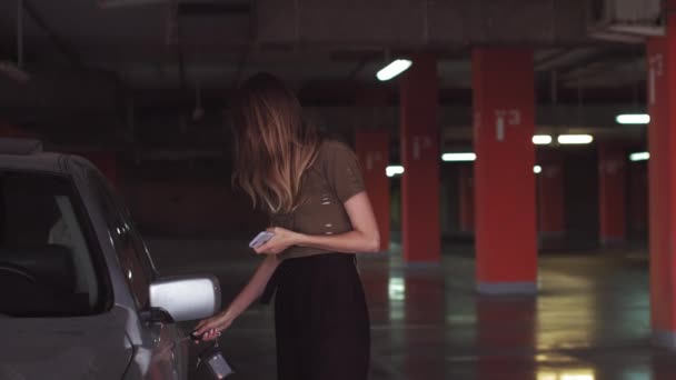 Una mujer atractiva utiliza una llave para abrir un coche en un estacionamiento subterráneo. Una chica guapa abre el coche. — Vídeos de Stock