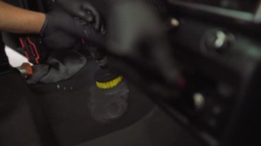 Kadın ve erkek arabalarını temizliyor, iki işçi arabanın içini dezenfekte ediyor. Arabanın içini kuru temizleme. Ayrıntılar çekiliyor