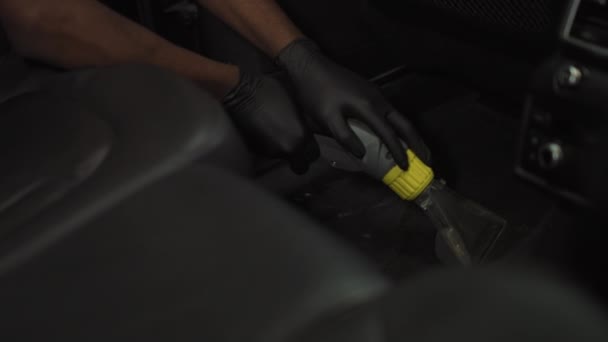 Un joven afroamericano limpia la alfombra del coche con un dispositivo especial, el trabajo para los estudiantes. Trabajo en el lavado de autos — Vídeos de Stock