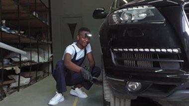 Siyah eldivenli yetişkin bir erkek eli için, sabunla araba tekerleğini temizlerken çekilen statik çekim. Hoş, genç, Afro-Amerikalı iş elbiseli adam tekerleri çamurdan bir fırçayla temizliyor.