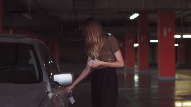 Çekici bir kadın yeraltı otoparkında araba açmak için anahtar kullanıyor. Güzel bir kız arabayı açar..