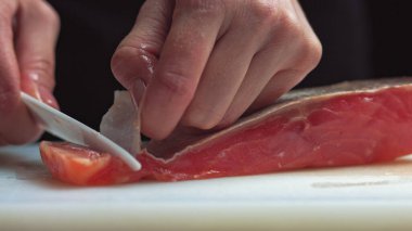 Suşi şefi suşi barında taze somon dilimler. Suşi adam Japon bıçağıyla somon bifteğini dilimliyor. Suşi nigiri balığı hazırlıyorum. Japon mutfak tarifleri..