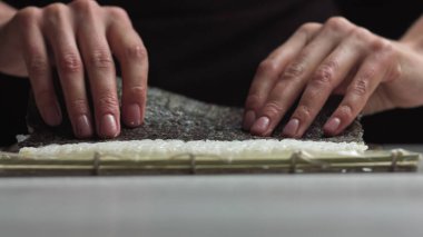 Suşi şefi lezzetli suşi ruloları için Norveç çarşafına Japon suşi pilavı seriyor. - Yüksek açılı atış.
