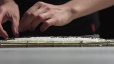 Suşi şefi lezzetli suşi ruloları için Norveç çarşafına Japon suşi pilavı seriyor. - Yüksek açılı atış.