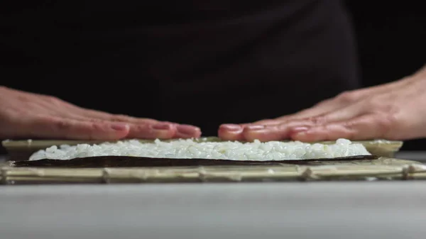 Sushi Chef Spreading Japanese Sushi Rice On Nori Sheet For A Delicious Sushi Rolls. - high angle shot