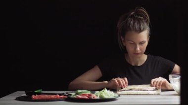 Eldivenli şef hasırla suşi pişiriyor. Maki pilav, yosun, salatalık ve krem peynirden yapılır. İştah açıcı ve besleyici Japon yemekleri..