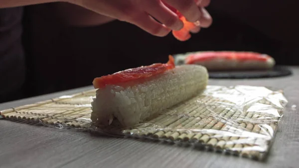 在日本正宗餐馆工作时，用竹子垫滚动新鲜寿司的匿名厨师手，用竹子垫滚动寿司卷的厨师手。寿司制作过程 — 图库照片