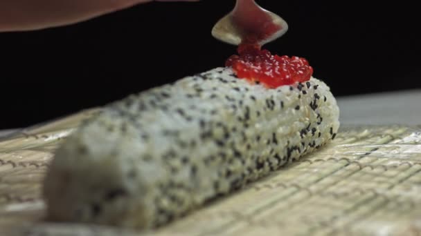 Séf A Roe Red Sushi kaviár felrakása a garnélarák tetejére Tempura Sushi Roll Avocado szeletekkel Teaspoon segítségével - közelről, panning shot — Stock videók