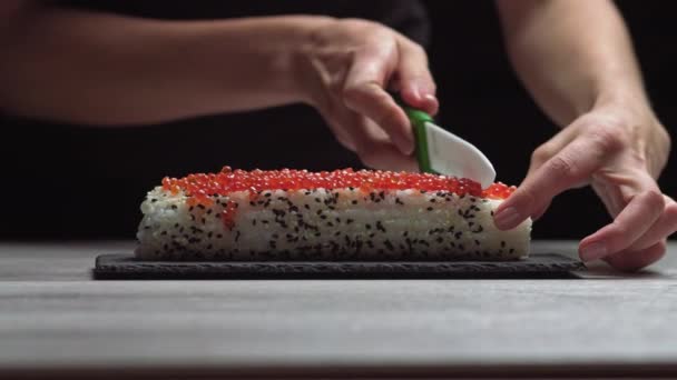 Šéf krájí sushi maki ostrým nožem na kousky. Proces sushi maki vaření, příprava. Japonská kuchyně. — Stock video