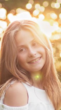 Sıcak güneş ışığıyla yıkanmış, mutluluk ve masumiyet saçan gülümseyen genç bir kızın güzel dikey portresi..