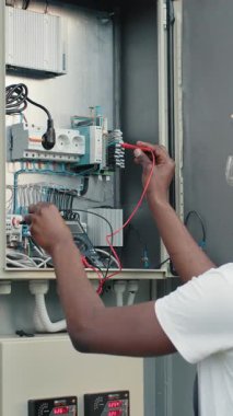 An electrician uses a multimeter to test an electrical panel, ensuring proper functionality and safety. This is a vertical video.