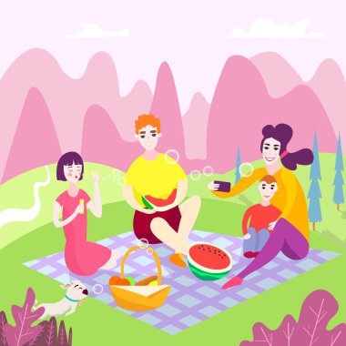 Parkta aile pikniği. Bahar tatili. Çocuklu mutlu bir aile. Onlar oturup parkta çim üzerinde karpuz yemek, çocuklar için yiyecek ve oyuncak ile bir sepet. selfie'ler çekin. Fırlatma sabun kabarcıkları.