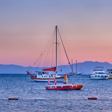 12 Temmuz 2022, Bodrum, Türkiye. Gün batımında Ege Denizi ve Adası manzarası, Yat ve tekneler rıhtımda duruyor.