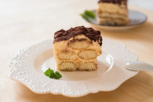 Postre tiramisú italiano sobre un plato de porcelana sobre un fondo de madera — Foto de Stock