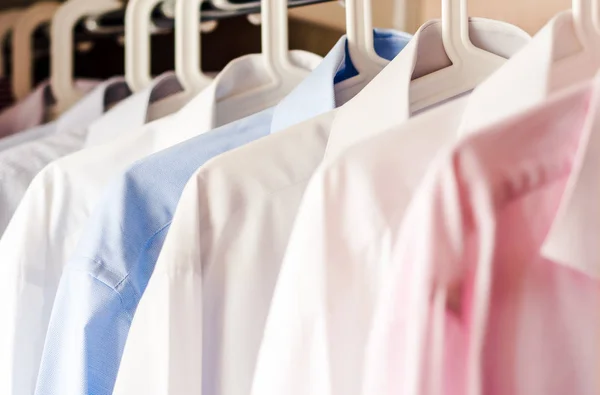 Fondo borroso de camisas blancas colgando en el armario — Foto de Stock