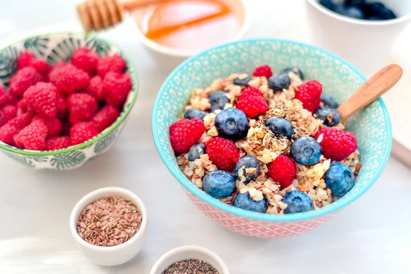 High protein healthy breakfast, buckwheat porridge with blueberries, raspberries, flax seeds and honey Closeup view