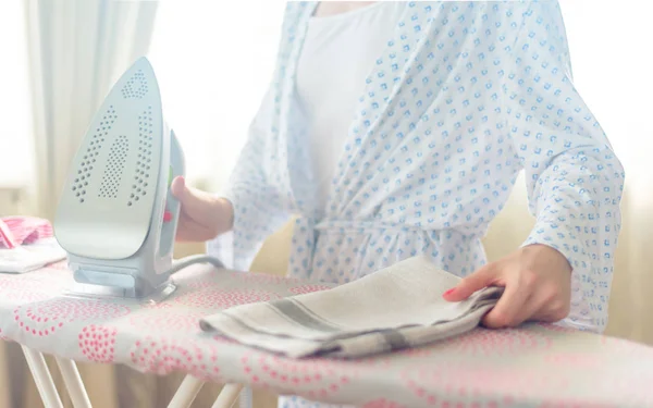 Primer plano de la mujer planchando la ropa en la tabla de planchar —  Fotos de Stock