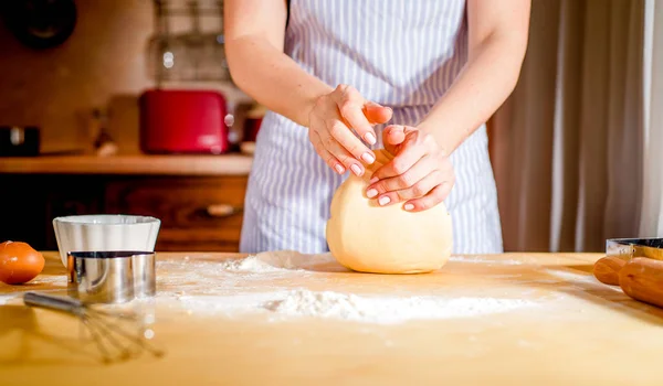 Las manos femeninas amasan la masa sobre la mesa —  Fotos de Stock