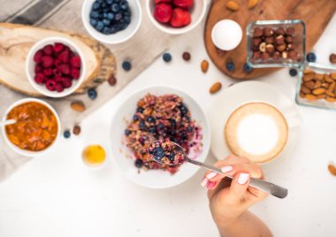 Üstten Görünüm gösteren eller, bal fındık ile yulaf lapası yemek yaban mersini üzerinde tablo beyaz.