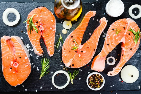 Two salmon steak, butter, pepper and salt, lemon, herbs border ,place for text on wooden rustic background top view