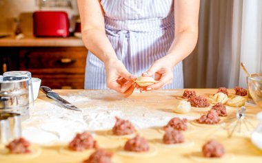 woman makes dumplings at home on kitchen table, close up clipart