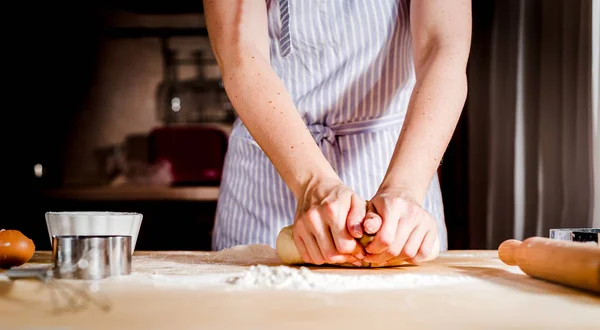 Mãos femininas fazendo massa na mesa de madeira — Fotografia de Stock