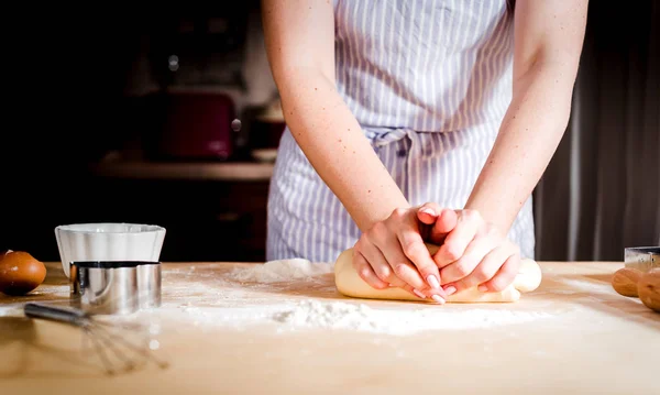 Mains féminines faisant de la pâte sur une table en bois — Photo