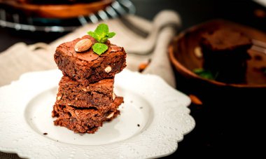 Parça ev yapımı karanlık çikolatalı kek ile badem dilimleri tepesi yığını ve nane kopya alanı ahşap tablo.