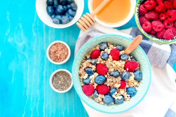 High protein healthy breakfast, buckwheat porridge with blueberries, raspberries, flax seeds and honey Closeup view, selective focus