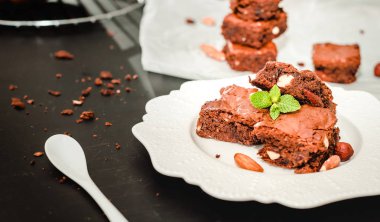 Parça ev yapımı karanlık çikolatalı kek ile badem dilimleri tepesi yığını ve nane kopya alanı ahşap tablo.