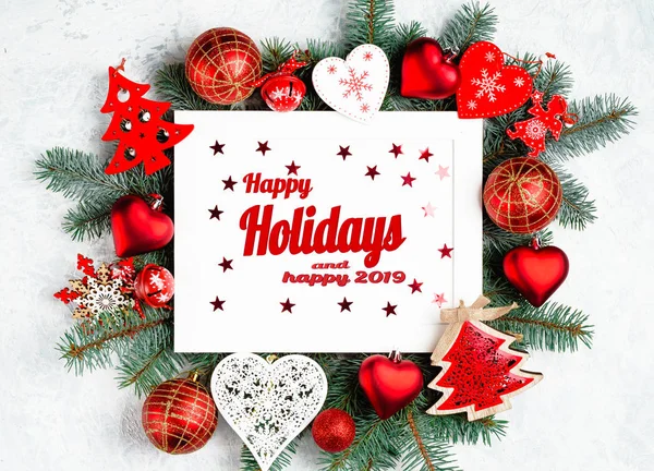 Boas festas e texto feliz de 2019 com fotomoldura de Natal cercada por ramos de uma árvore de Ano Novo, decorações de Natal vermelhas. Vista superior, flat lay . — Fotografia de Stock