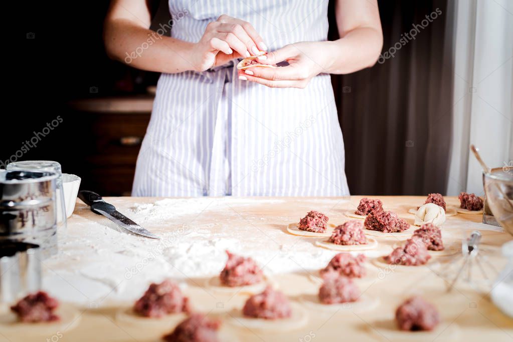 woman makes dumplings at home on kitchen table, close up