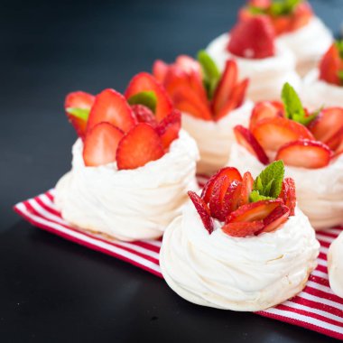 Çilek pavlova kek yuvaları, siyah masada nane ile