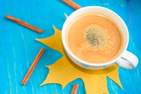 Composición de café de otoño, taza de café con espuma, canela, hoja de otoño en fondo azul. Bebidas calientes de otoño, café y concepto de bar — Foto de Stock