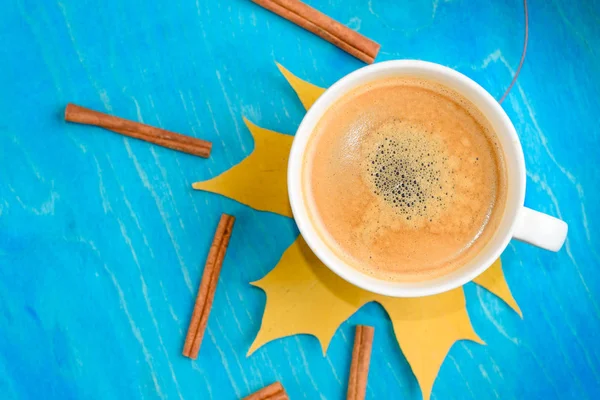Composición de café de otoño, taza de café con espuma, canela, hoja de otoño en fondo azul. Bebidas calientes de otoño, café y concepto de bar — Foto de Stock