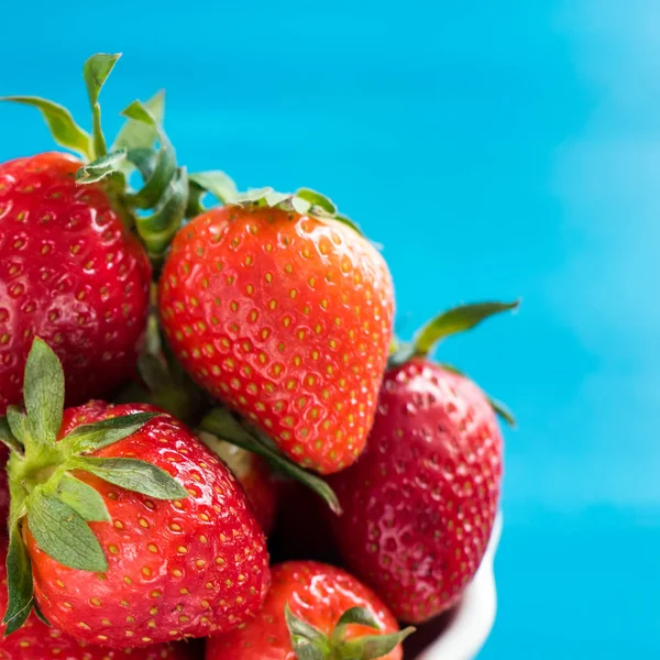 Frische helle Erdbeeren in einer Schüssel Draufsicht auf blauem Hintergrund — Stockfoto