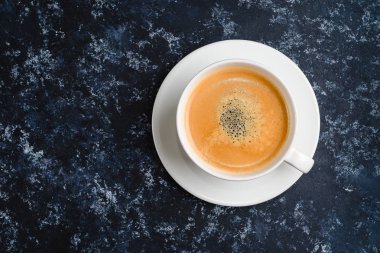 Siyah üzerine beyaz bir fincan kahve. Üst görünüm, ahşap masa üzerinde fincan, mola veya kahvaltı