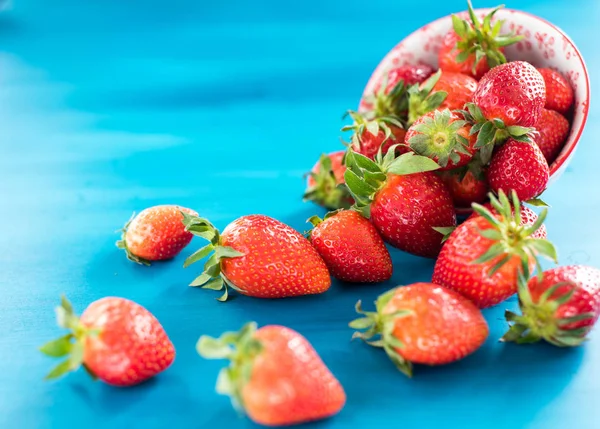 taze parlak çilek mavi bir arka plan üzerinde kase dışarı dökülen