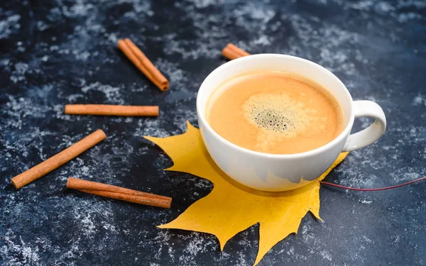 Осенний состав кофе, чашка кофе с пеной, корица, осенний лист на черном фоне. Осенние горячие напитки, концепция кафе и бара — стоковое фото