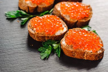 Ekmek arası arduvaz arka plan üzerinde kırmızı havyar.