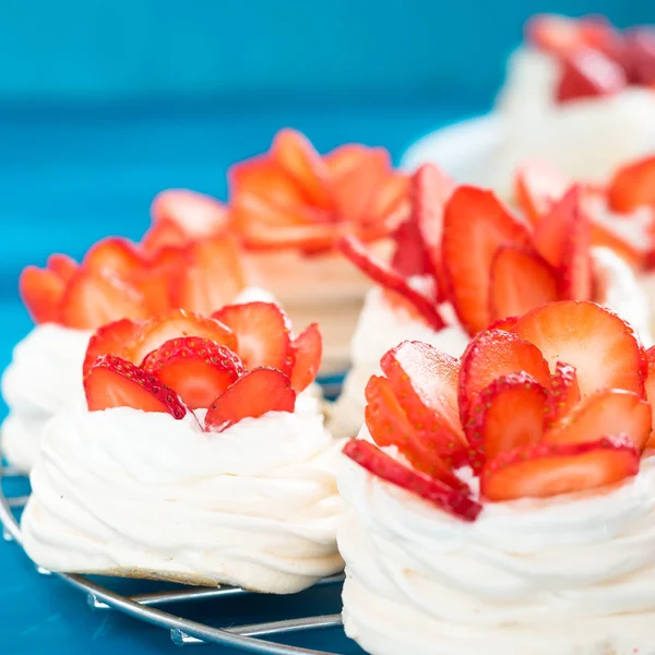 Gyönyörű Pavlova sütemények eper kék háttér. Szelektív fókusz. Ízletes édes breackfast. Esküvő reggel. Habcsók tejszínnel. — Stock Fotó