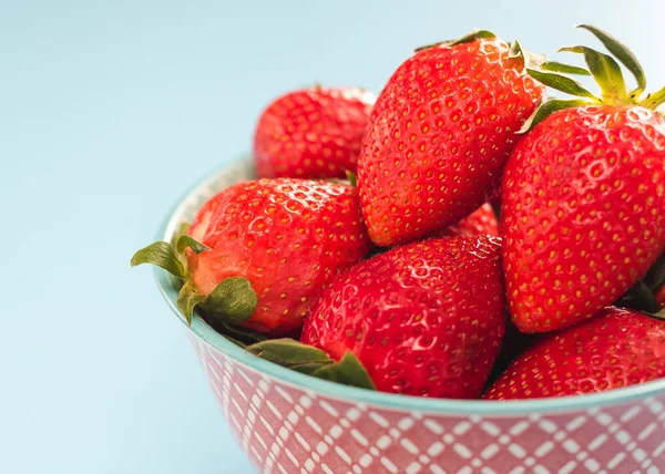 Bunte reife Erdbeeren in einer hellen Schüssel auf blauem Hintergrund — Stockfoto