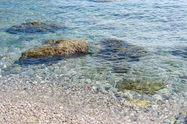 Hintergrund aus transparentem Meerwasser und Boden, mit Steinen und Wellen — Stockfoto
