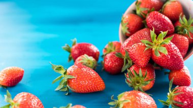 taze parlak çilek mavi bir arka plan üzerinde kase dışarı dökülen