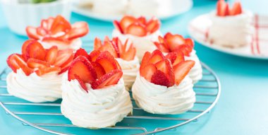 Beautiful pavlova cakes with strawberries on a blue background. Selective focus. Tasty sweet breackfast. Wedding morning. Meringue with cream. clipart