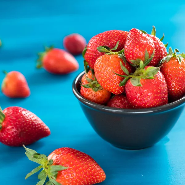 Frische helle Erdbeeren in einer Schüssel Draufsicht auf blauem Hintergrund — Stockfoto