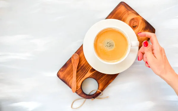Mains féminines avec une tasse de café avec mousse sur une table grise en bois, vue sur le dessus — Photo